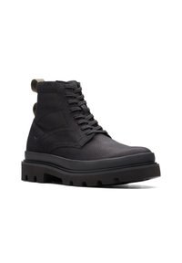 Botas negras por encima del tobillo, hechas de cuero texturizado y tela con suela de goma resistente, que presentan un cordón frontal y una lengüeta en la parte posterior.