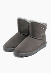 Stivali alla caviglia in suede grigio con una morbida fodera in pelliccia e borchie decorative su un lato. Punta arrotondata e suola in gomma per la presa.
