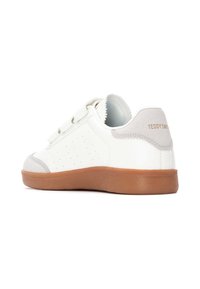 Sneaker blanche avec des accents en daim gris, panneau latéral perforé, semelle en caoutchouc gomme et sangles velcro. Nom de la marque "TEDDY SWIMS" embossé au niveau du talon.