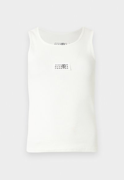 Bijeli majica bez rukava s rebrastom teksturom i malom etiketom na kojoj su brojevi i krug. Jednostavan, klasičan dizajn.