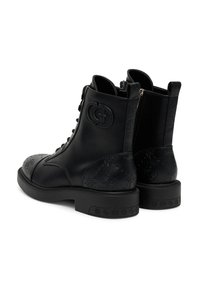 Stivaletti neri in pelle con logo in rilievo, stringati sul davanti e con cerniere laterali. Presentano un retro testurizzato e suole in gomma spesse e piatte.