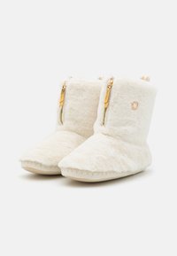 White fur-lined boots with a soft texture, featuring a pointed toe, gold zippers, and stitched detailing on the sole.