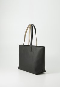 Sac fourre-tout en cuir noir texturé avec deux poignées, présentant un accent beige lisse sur les poignées et un détail de poche à l'avant.