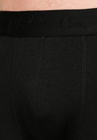 Zwarte katoenen boxershorts met een zachte textuur, voorzien van een zwarte elastische tailleband waarop "Phil & Co." in cursieve lettertype is geborduurd.