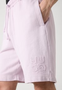 Lyserøde bomuldsshorts med elastisk linning, sidelommer og hævet broderi af "HUGO" på venstre ben. Casual design.