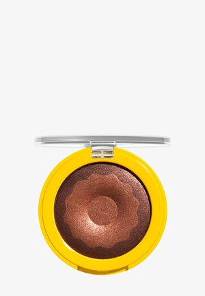 Palette de maquillage compacte avec un couvercle transparent contenant une poudre pressée scintillante en bronze et cuivre, disposée en cercle avec des bords festonnés.