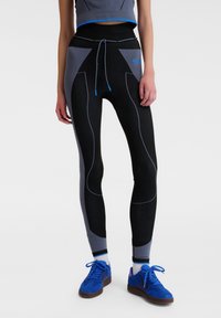 Zwarte en grijze sportleggings met textuurpanelen, een verstelbare trekkoordtaille, blauwe accenten en een getailleerde pasvorm.