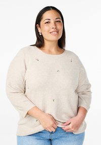 Beige gestrickter Pullover mit Dreiviertelärmeln, der kleine rosa Blumenstickereien aufweist, eine weiche Textur hat und einen runden Ausschnitt besitzt.