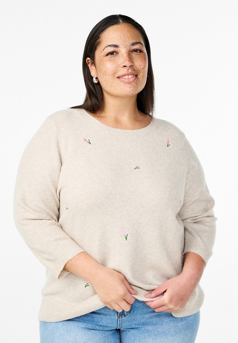 Beige gestrickter Pullover mit Dreiviertelärmeln, der kleine rosa Blumenstickereien aufweist, eine weiche Textur hat und einen runden Ausschnitt besitzt.
