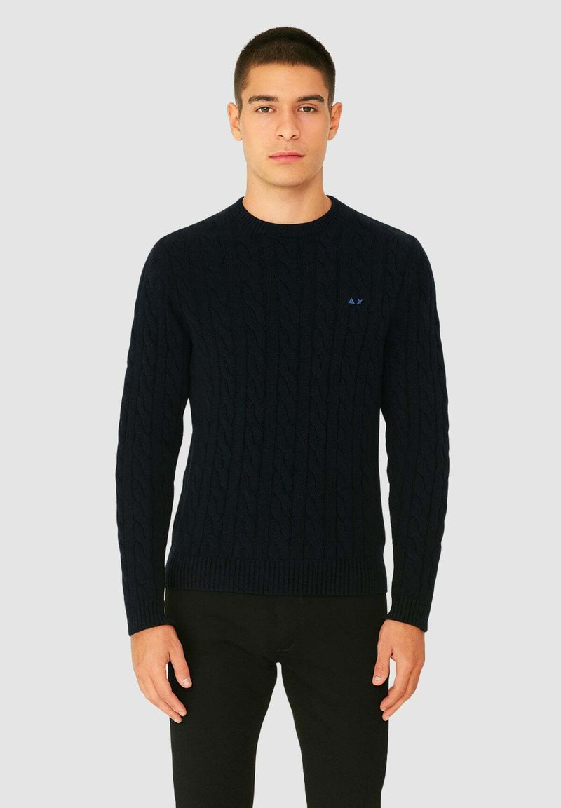 Maglione blu navy a trecce con colletto rotondo, polsini e orlo a costine, caratterizzato da un piccolo logo blu sul lato sinistro del petto.
