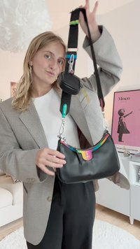 Zwarte schoudertas met een regenboogkleurige ritsaccent en een aangehechte kleine zak. Voorzien van zilverkleurig beslag en een afneembare, verstelbare schouderriem.