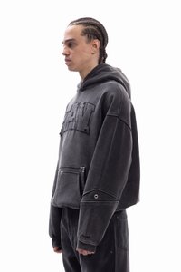 Γκρι φούτερ με κουκούλα από υφασμάτινη υφή, υπερμεγέθη σχεδιασμό και τσέπη μπροστά. Διαθέτει κεντημένα γράμματα και διακοσμητικά ανοίγματα στα μανίκια.