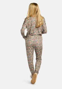 Pyžamový set s dlhými rukávmi, vyrobený z svetlohnedého materiálu s farebným vzorom zvierat a kvetov. Elastický pás a priliehavé manžety. Ľahká textúra.