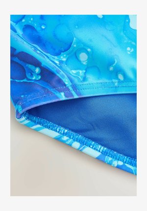 Lähedal pilt sinisest kangast, millel on veepiisade muster ja detailne õmblus servas.