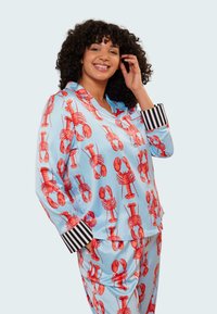 Pajamaset med hummermönster i ljusblå satin, med röda humrar och svartvita randiga mudd. Bekväm passform med knappstängning.