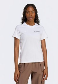 Balta kokvilnas T-krekls ar apaļu kakla izgriezumu, uz krūtīm pelēks TERREX logotips. Īsas piedurknes un standarta piegriezuma dizains.