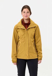 Kollane veekindel jakk, millel on lukuga esikülg, reguleeritav kapuuts ja mitu taskut, kantud punase fliisi peal. Sile tekstuur.