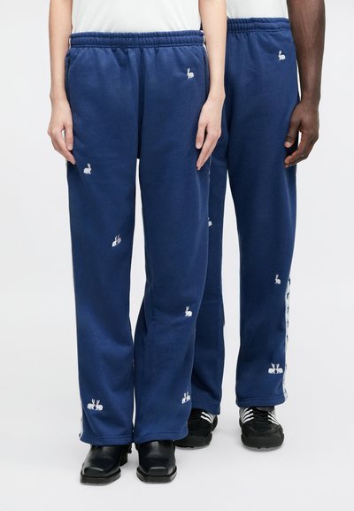 Navy sweatpants featuring a relaxed fit, elastic waistband, side pockets, and small white rabbit embroidery on the front and sides.