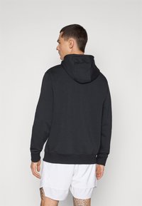 Black hoodie with a front kangaroo pocket, ribbed cuffs, and hem. Soft fabric with a smooth texture. Features a drawstring hood.