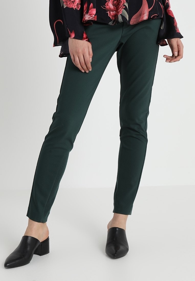 Gröna slim fit-byxor i ett elastiskt material, med en mjuk textur och en stilren silhuett. Bärs tillsammans med svarta öppna mules.