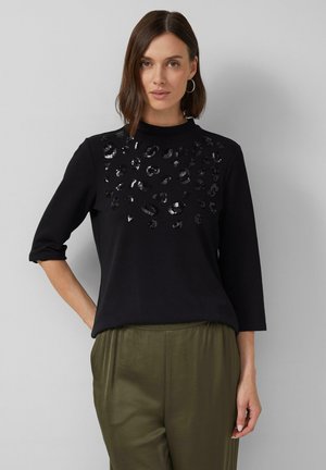 Haut noir à manches trois-quarts, doté d'un design en imprimé animal texturé et sequins sur la poitrine. Tissu doux, coupe décontractée.