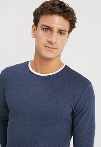 Granatowa koszula z długim rękawem z miękkiego materiału, z białym okrągłym dekoltem. Slim fit z gładką fakturą i minimalnymi detalami.