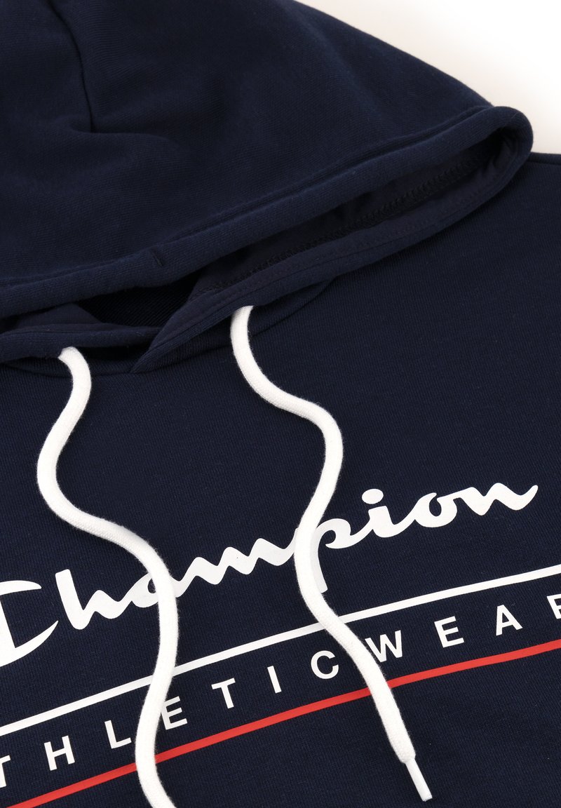 Felpa con cappuccio blu navy con lacci bianchi, caratterizzata da un grande logo "Champion" bianco e rosso sulla parte anteriore. Materiale in cotone, design casual.
