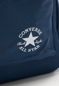 Κοντινό πλάνο υφάσματος σε ναυτικό μπλε χρώμα με το λευκό λογότυπο Converse All Star Chuck Taylor που απεικονίζει ένα μεγάλο αστέρι στο κέντρο.