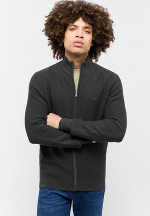 Sudadera gris oscuro con cremallera y textura acanalada, cuello alto y mangas largas, combinada con una camiseta interior verde claro y jeans azules.