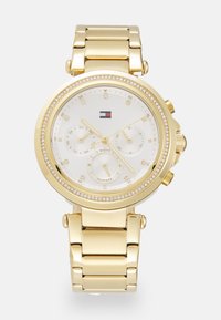 Orologio da polso color oro con quadrante bianco, dettagli in cristallo e bracciale in metallo. Presenta più quadranti e un display della data. Logo del brand incluso.