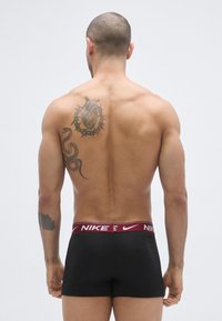 Μαύρα βαμβακερά ανδρικά εσώρουχα μπόξερ με μαροον λωρίδα μέσης Nike, με απαλό υφή και εφαρμοστό σχεδιασμό. Εμφανίζει τατουάζ στην πλάτη.