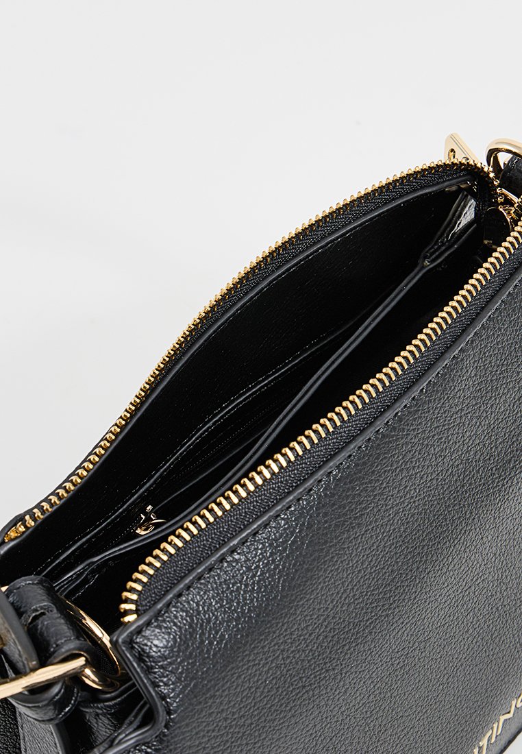 Schwarze Lederhandtasche mit goldenen Reißverschlussdetails; das Innere verfügt über mehrere Fächer zur Organisation. Glatte Textur mit robuster Konstruktion.