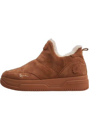 Scarpe slip-on in camoscio marrone con rivestimento in pelliccia sintetica, suola in gomma testurizzata e un branding sottile sui lati e sul tallone. Design mid-top.