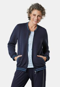 Marine gewatteerde jas met een ritssluiting aan de voorkant, ribgebreide manchetten en kraag met teal strepen, twee zijzakken en een comfortabele pasvorm.