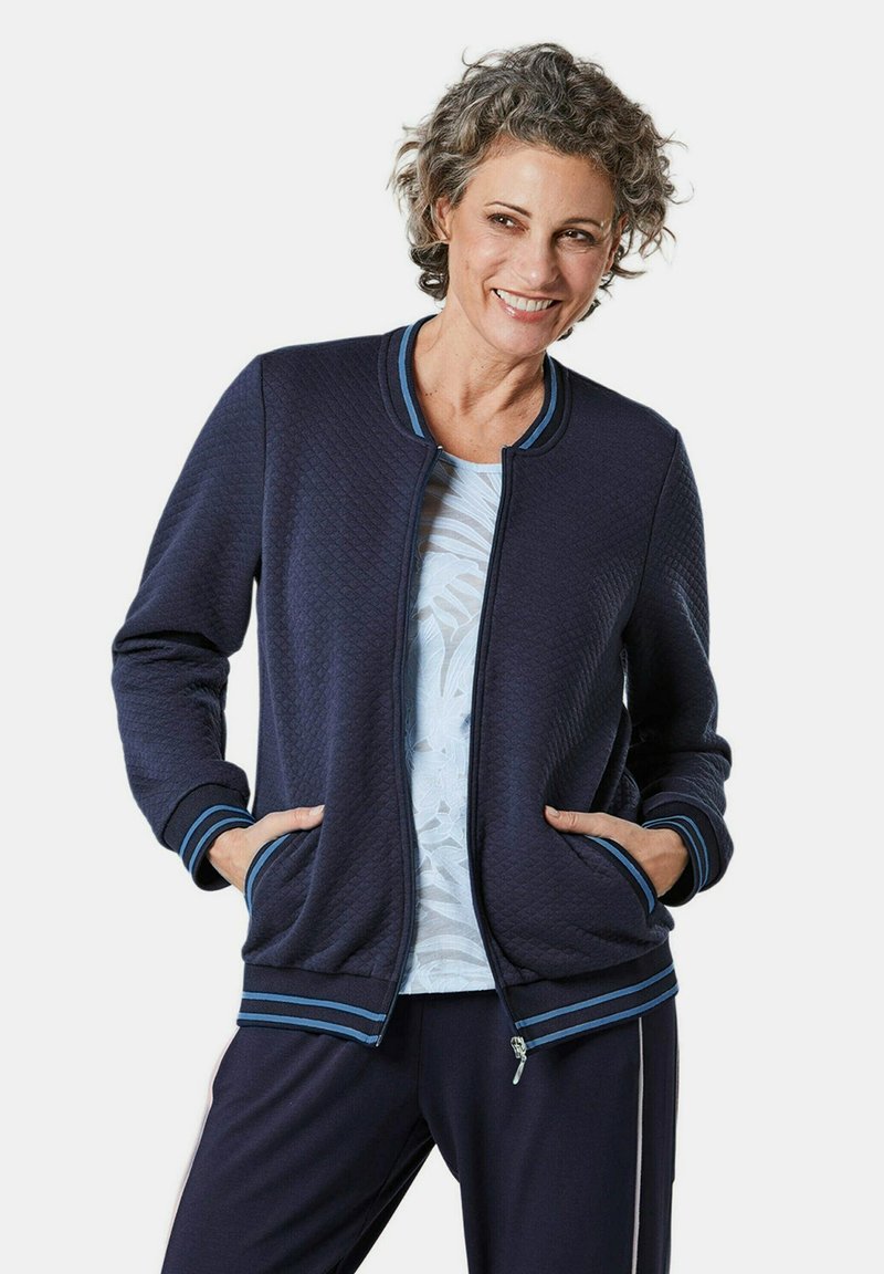 Marine gewatteerde jas met een ritssluiting aan de voorkant, ribgebreide manchetten en kraag met teal strepen, twee zijzakken en een comfortabele pasvorm.