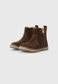 Botines de ante marrón con cremallera lateral, punteras redondeadas, forro interior color crema y suelas de goma texturizadas con un diseño cosido.