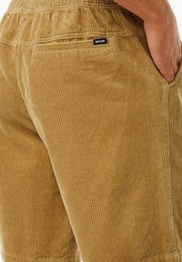Samtshorts in einem tanfarbenen Ton mit gerippter Textur. Features einen elastischen Bund und eine Gesäßtasche mit einem kleinen Markenlabel.