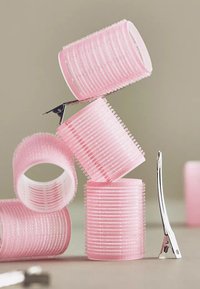 Rulos de pelo rosas apilados con un clip de metal plateado, que presentan una textura acanalada y un material suave y aterciopelado para un mejor agarre.