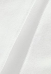 Weiße Baumwollstoffe mit glatter Textur, leichtem Glanz und sichtbaren Nähten entlang der Kanten, schräg gefaltet.