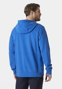 Sudadera azul con capucha ajustable, puños y cinturilla acanalados. Fabricada en tejido suave, con una textura lisa y un corte casual.