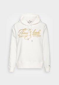 Felpa bianca realizzata in tessuto morbido, con logo ricamato in oro "New York Tommy Hilfiger" e cordini per il cappuccio.
