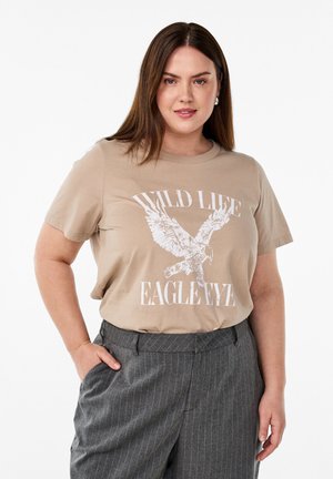 Béžové tričko s bílou grafikou orla a textem "WILD LIFE EAGLE EYEZ." Krátké rukávy, kulatý výstřih, vyrobeno z měkkého bavlněného materiálu.