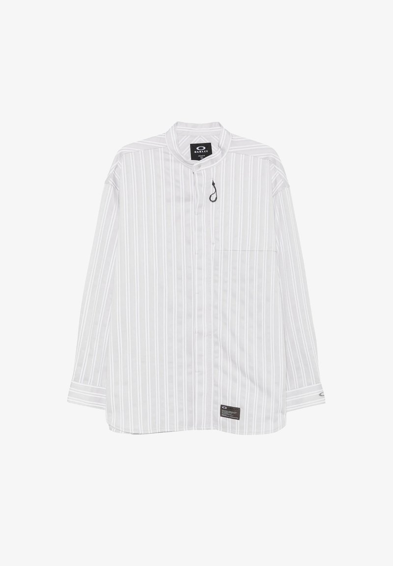 Camicia bianca a maniche lunghe con sottili righe verticali grigie, una piccola tasca frontale e un'etichetta nera vicino all'orlo e al colletto.