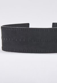 Banda de cuero negro con acabado mate, que presenta un patrón texturizado de cuadrados y acentos rectangulares a lo largo de los bordes.