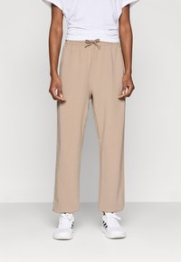 Ανοιχτόμπεζ φόρμας με ελαστική μέση και κορδόνι. Άνετη εφαρμογή, ευθεία γραμμή στα πόδια, κατασκευασμένη από μαλακό βαμβακερό μείγμα.