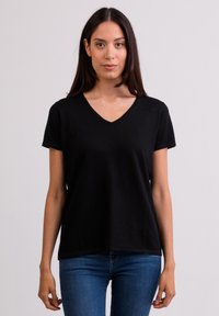 T-shirt nera a V con maniche corte, realizzata in un tessuto morbido. Vestibilità comoda, caratterizzata da un design semplice e dettagli minimal.
