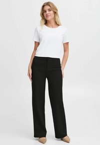 Black wide-leg trousers made of soft fabric with a smooth texture, featuring a button closure and side pockets. Paired with a plain white t-shirt.