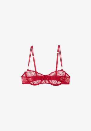 Red lace bra with sheer mesh cups, scalloped edges, and adjustable straps. Features a central bow and decorative hardware accents.