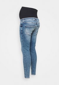 Těhotenské džíny ve světle modré denimové barvě, s vysokým černým elastickým pasem, slim fit střih, a zadními kapsami s mírným blednutím.