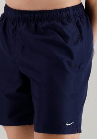 Pantaloni sportivi blu navy con elastico in vita, tasche laterali e un piccolo logo Nike bianco sull'orlo sinistro. Tessuto leggero.